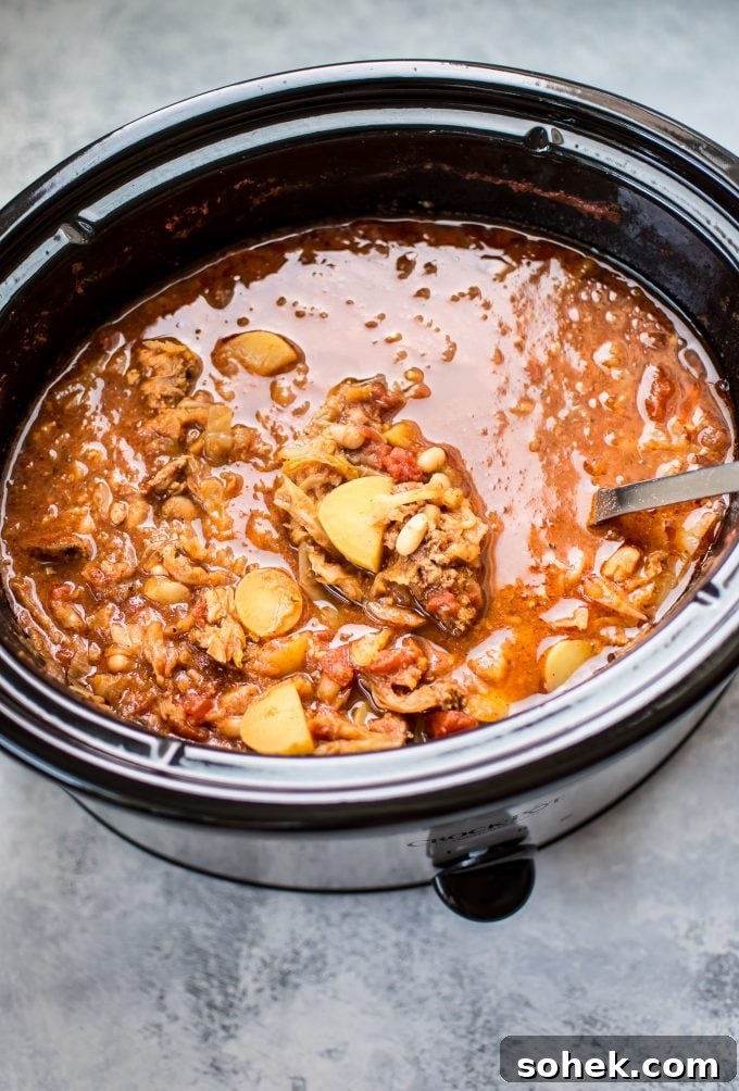 Hearty Crockpot Cabbage Soup with Sausage, Beans & Potatoes 3 cabbage soup with sausage in a slow cooker with ladle