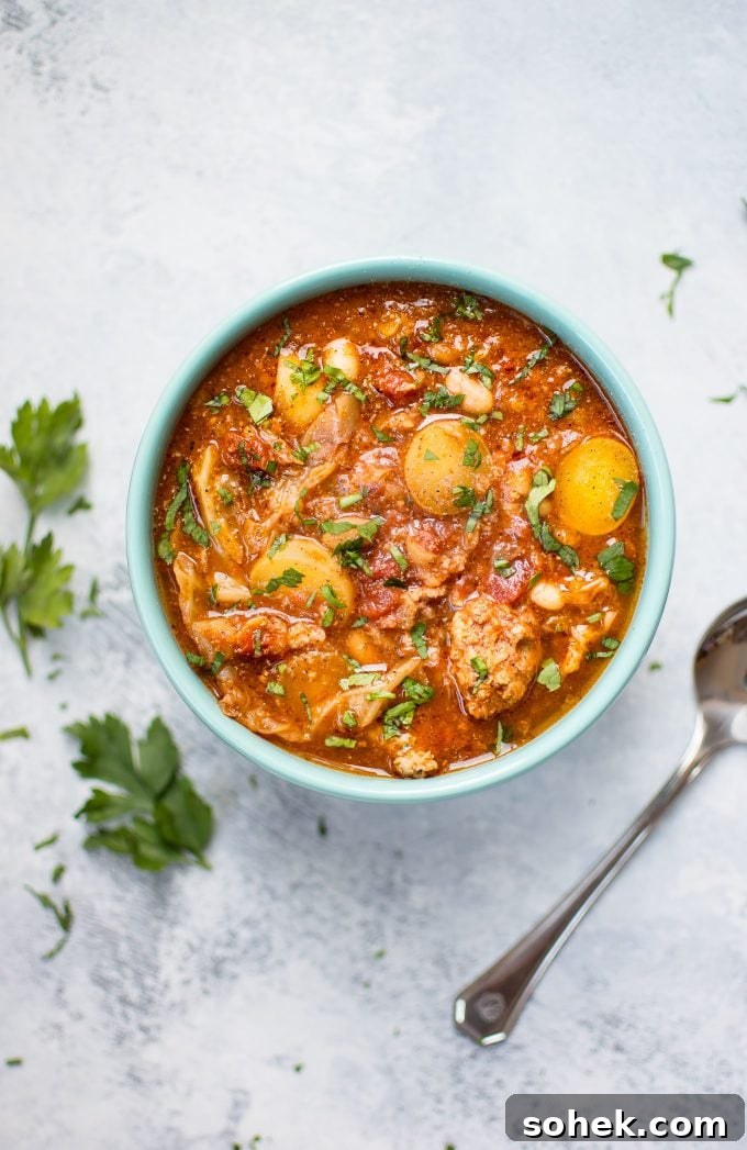 Hearty Crockpot Cabbage Soup with Sausage, Beans & Potatoes 4 bowl of Crockpot cabbage soup beside parsley sprigs and a spoon