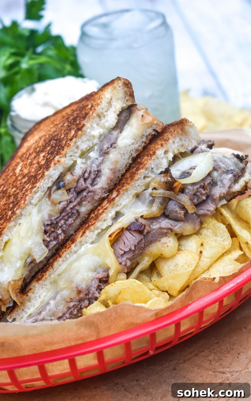two halves of roast beef grilled cheese with smoked gouda on a bed of potato chips in a red plastic food basket