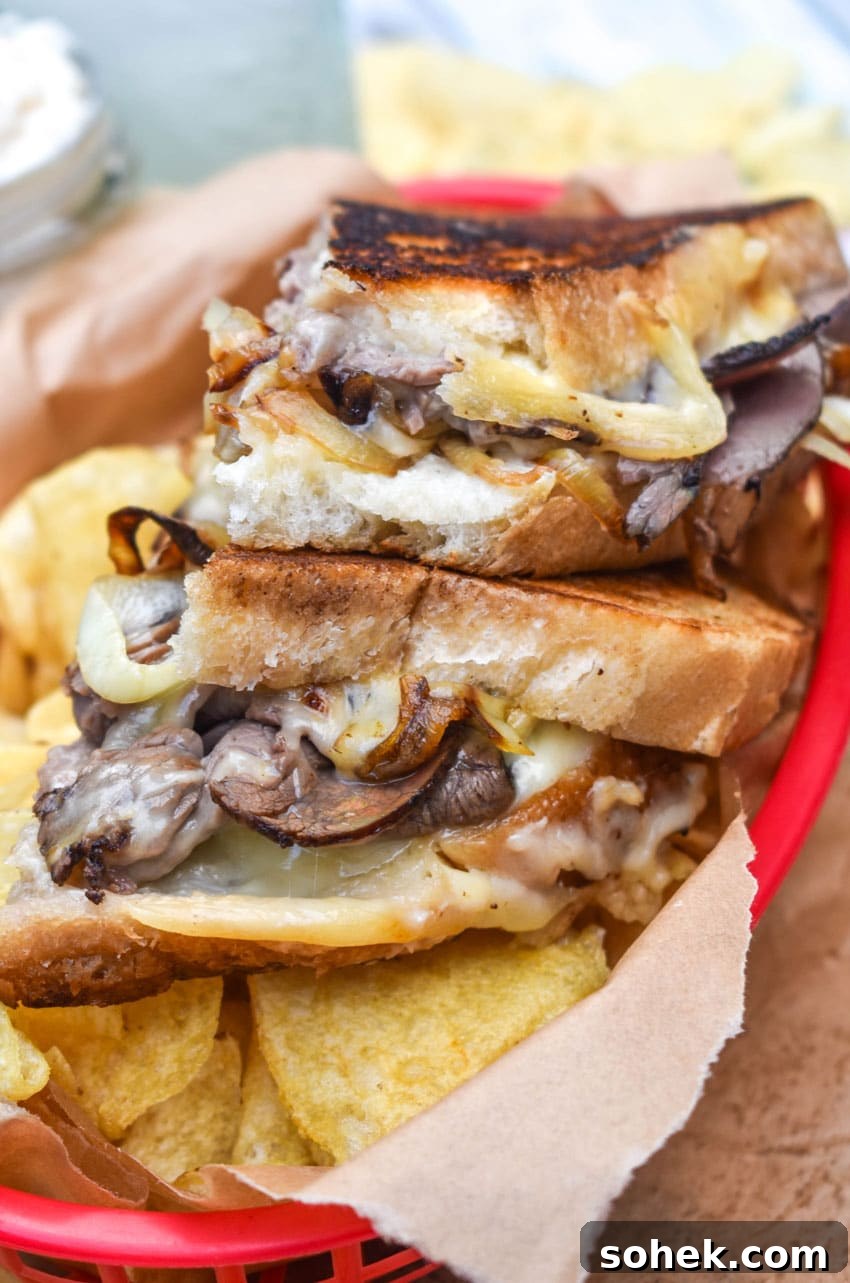 two halves of roast beef grilled cheese with smoked gouda on a bed of potato chips in a red plastic food basket