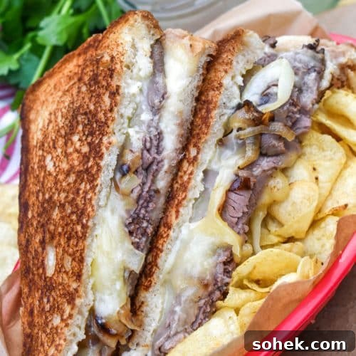 two halves of roast beef grilled cheese with smoked gouda on a bed of potato chips in a red plastic food basket