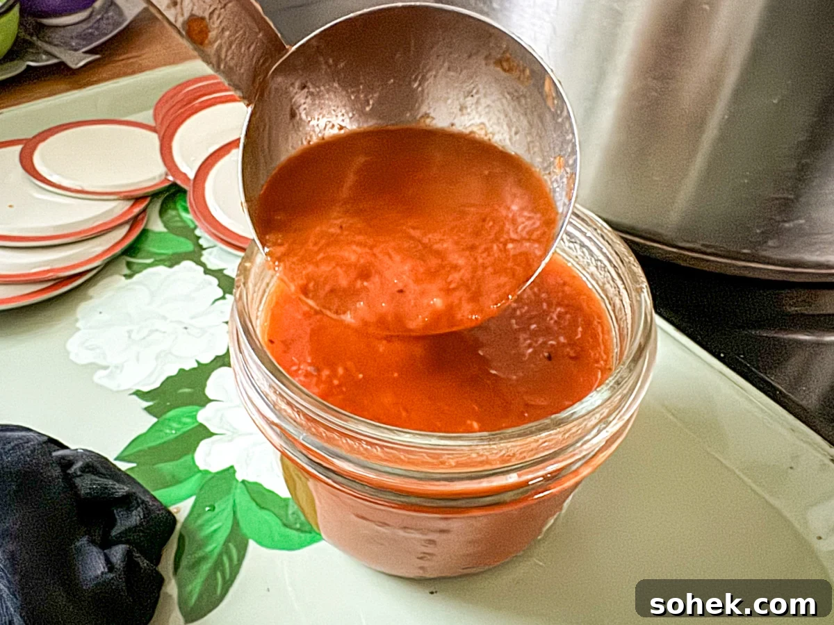 Canned Pizza Sauce from Fresh or Frozen Tomatoes — Simple Recipe 7 Adding pizza sauce to canning jar
