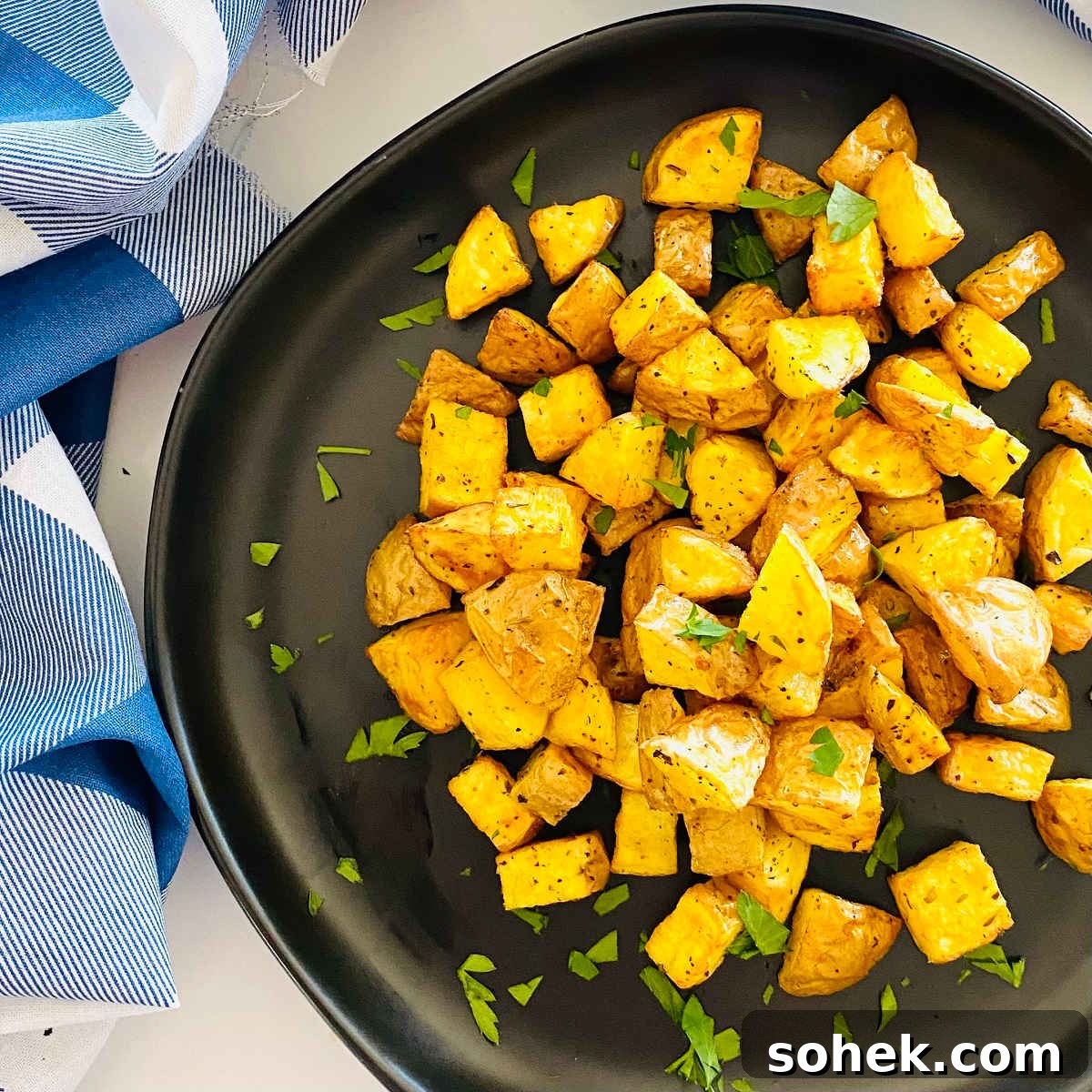 Crispy Air Fryer Diced Potatoes Recipe 6 air fryer diced potatoes on a plate with parsley garnish