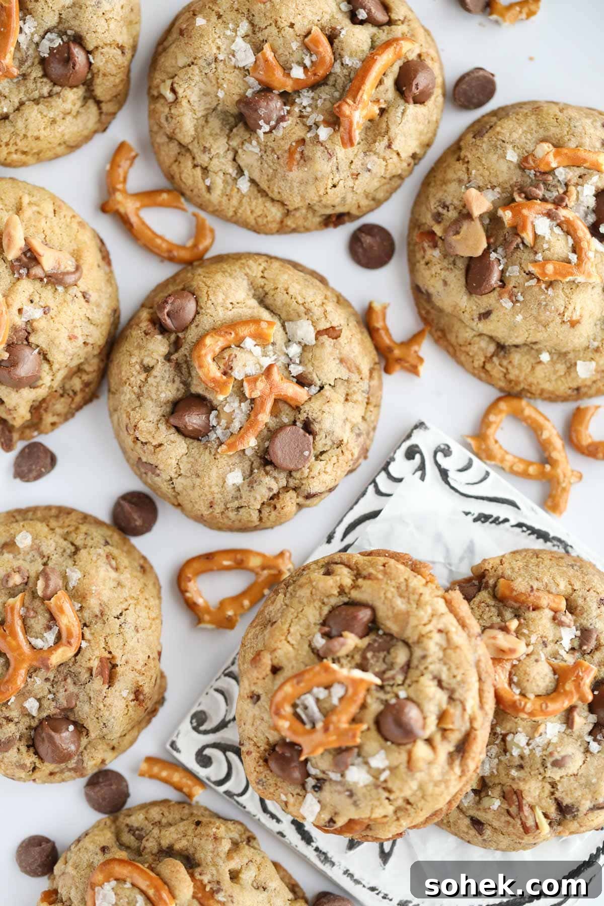 Ultimate Kitchen Sink Cookies Recipe: Loaded Chocolate Chip Bars 2 kitchen sink cookies spread out on a white surface.
