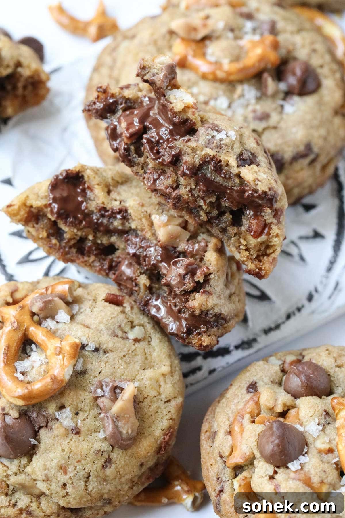 Ultimate Kitchen Sink Cookies Recipe: Loaded Chocolate Chip Bars 3 kitchen sink cookie broken open on a white surface.