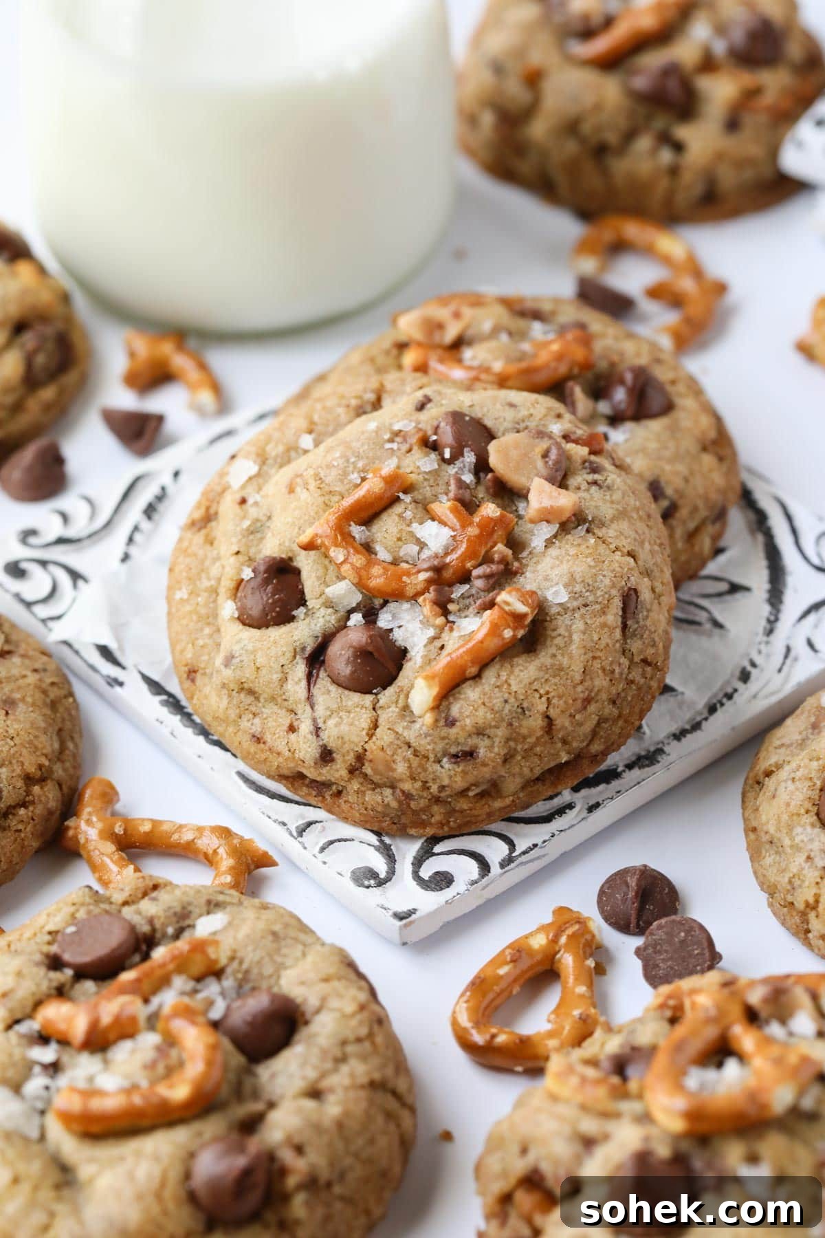 Ultimate Kitchen Sink Cookies Recipe: Loaded Chocolate Chip Bars 5 kitchen sink cookies on a white surface with a glass of milk in the background.