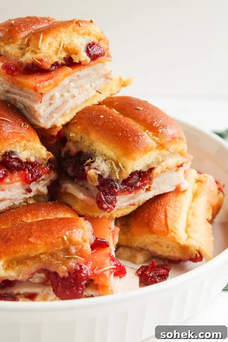 Turkey sliders with cranberry sauce and King's Hawaiian rolls stacked on a plate & ready to serve.