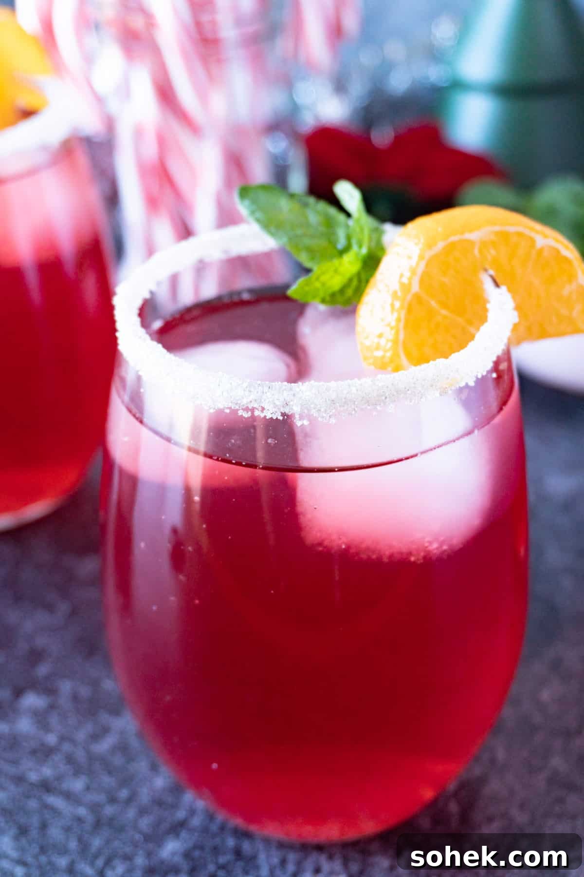 Cranberry Mint Julep Cocktail Recipe for Holiday Gatherings 2 Cranberry julep in glass with sugared rim and orange slice and mint leaves as garnish.