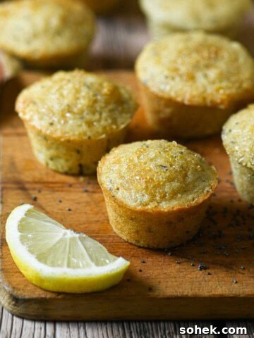 Six mini muffins on wood board with a lemon next to them.