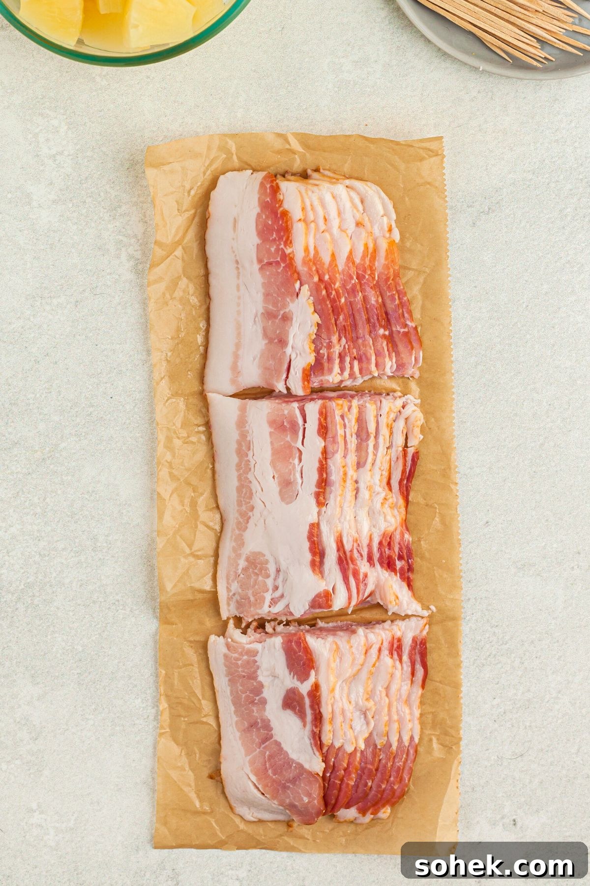 Crispy Air Fryer Bacon-Wrapped Pineapple Bites 4 Bacon slices cut into thirds on parchment paper
