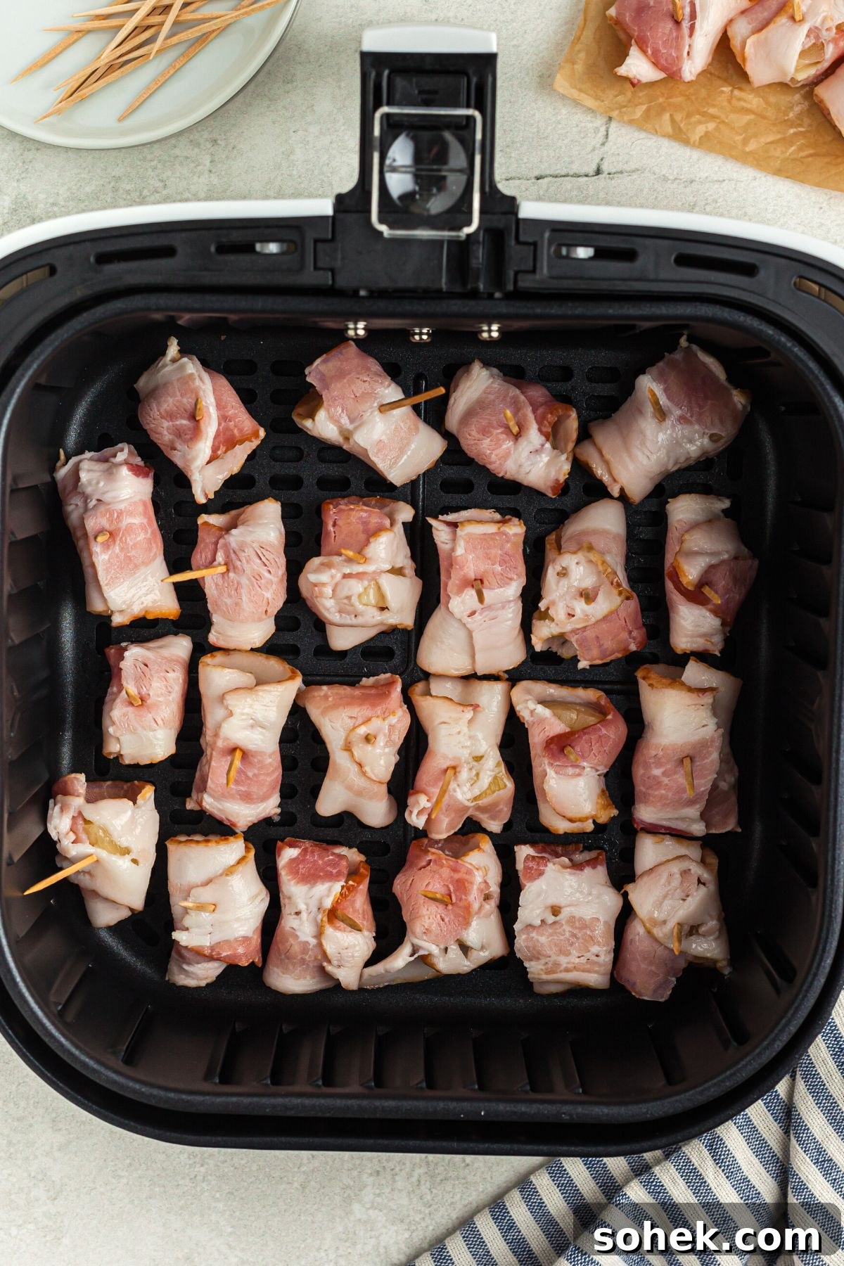 Crispy Air Fryer Bacon-Wrapped Pineapple Bites 6 Bacon wrapped pineapple bites in the air fryer basket before being air fried.