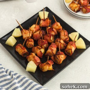 Crispy Air Fryer Bacon-Wrapped Pineapple Bites 8 Crispy bacon wrapped pineapple bites on a square black plate
