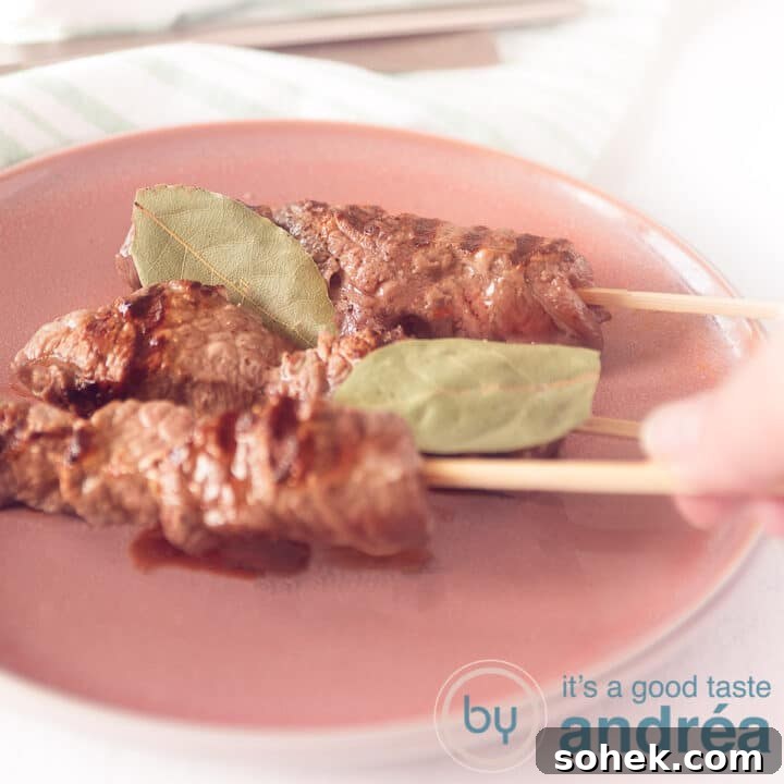A square photo with a pink plate on which three Portuguese grilled skewers. A hand takes a skewer