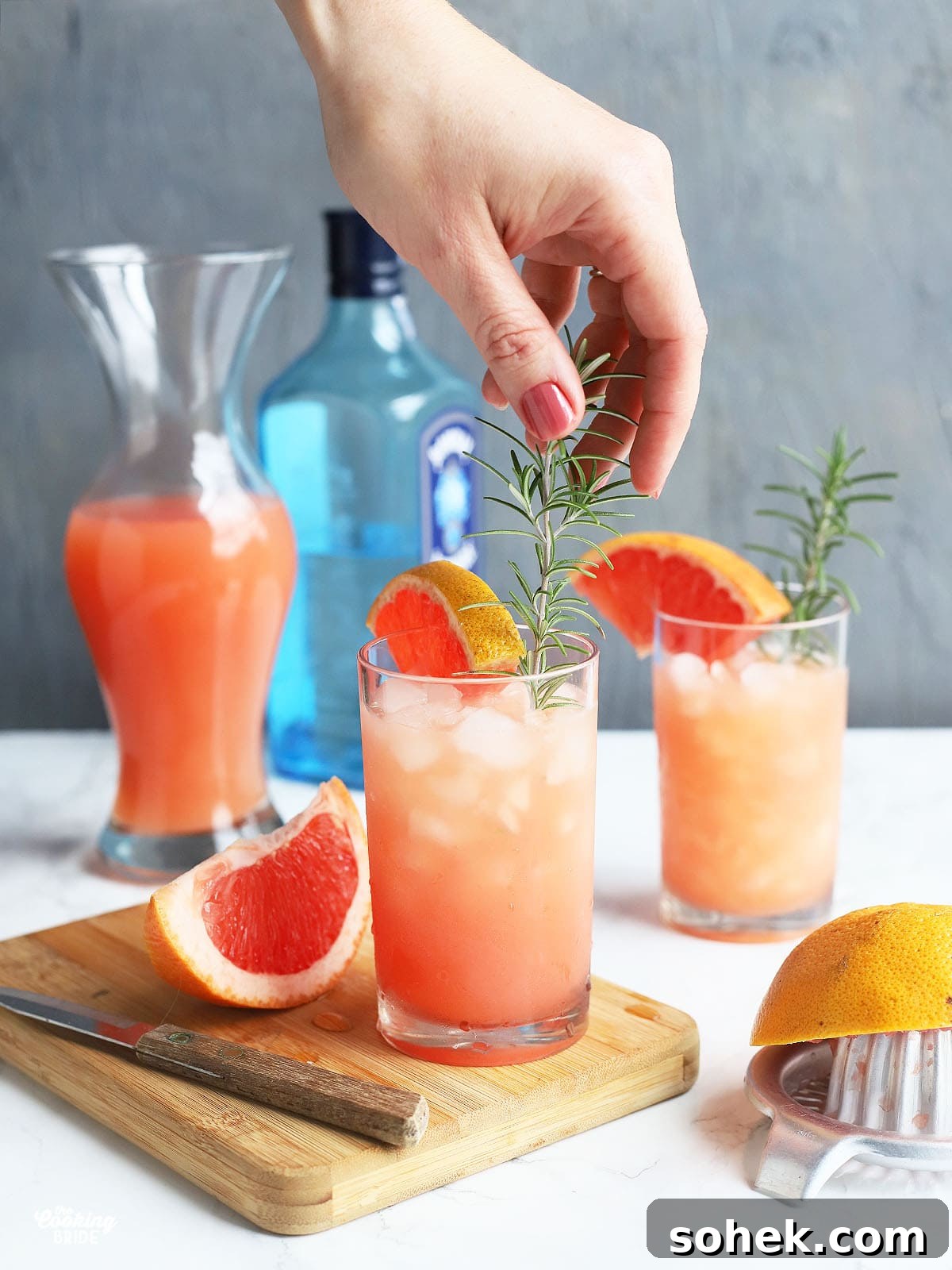 Rosemary Gin Grapefruit Cocktail Recipe with Citrus Twist 9 hand placing a sprig of rosemary in a cocktail glass