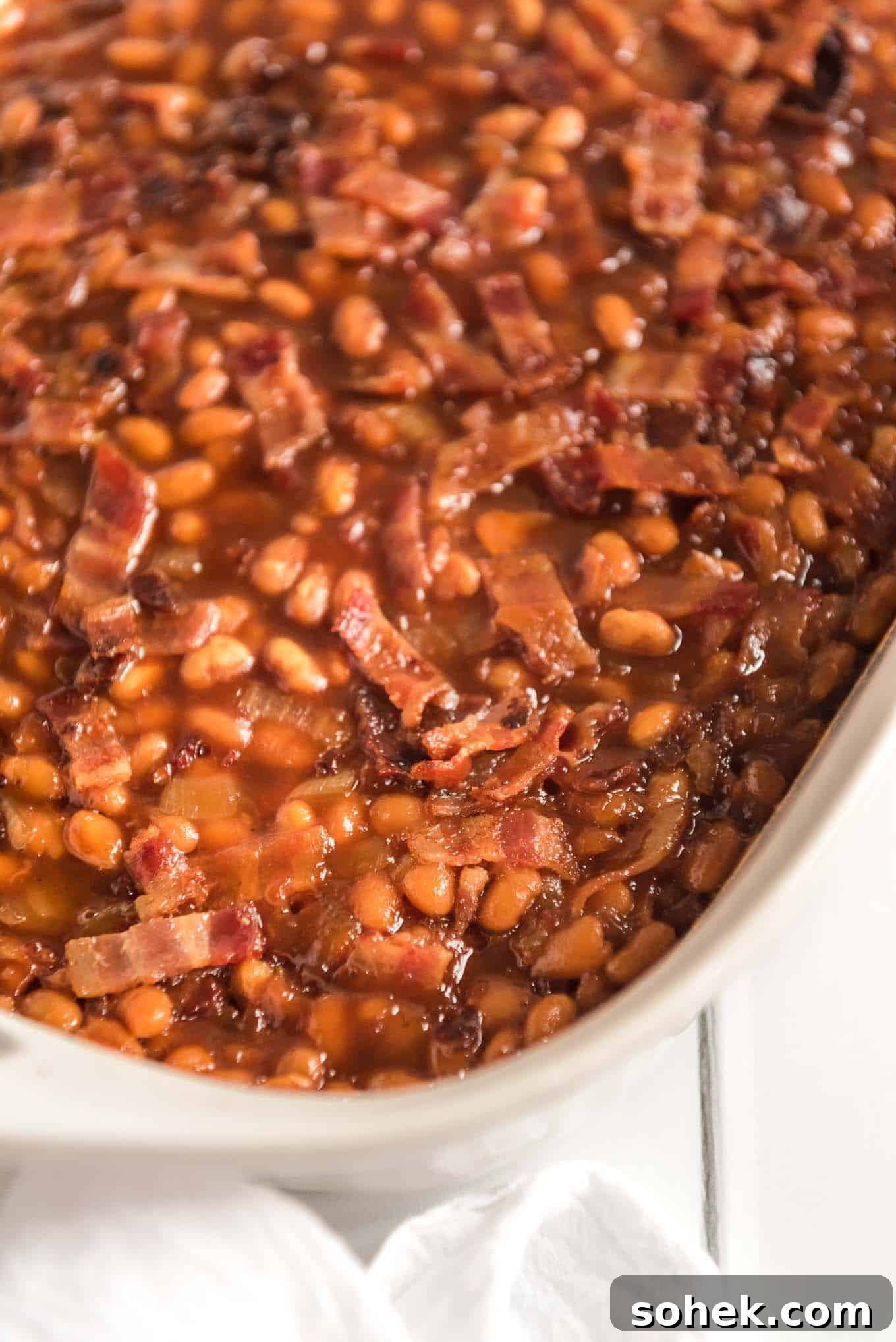 BBQ baked beans in a casserole dish topped with bacon.