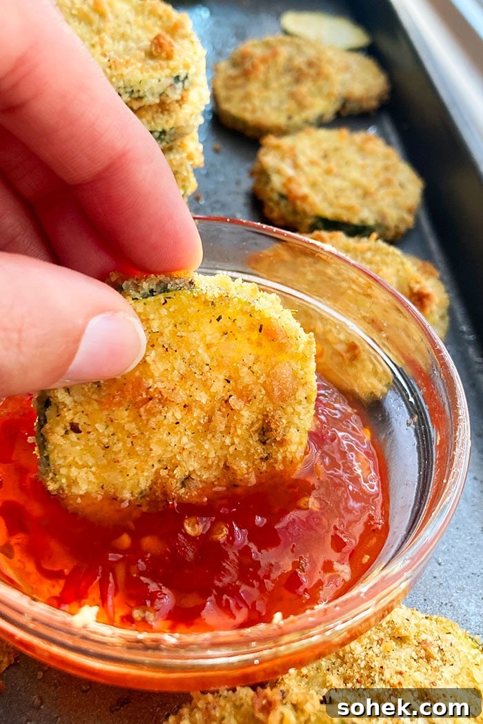 Crispy Oven-Baked Zucchini Chips (One-Pan Recipe) 4 Zucchini Crisps Being Dipped in Sweet and Spicy Sauce