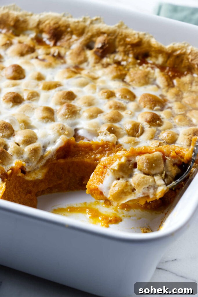 A spoon scooping a serving of sweet potatoes and marshmallows.