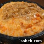 Pumpkin Pap (Sidvudvu): Traditional South African Maize Porridge 3 A bowl full of pumpkin pap served with a little cream sauce and onions.