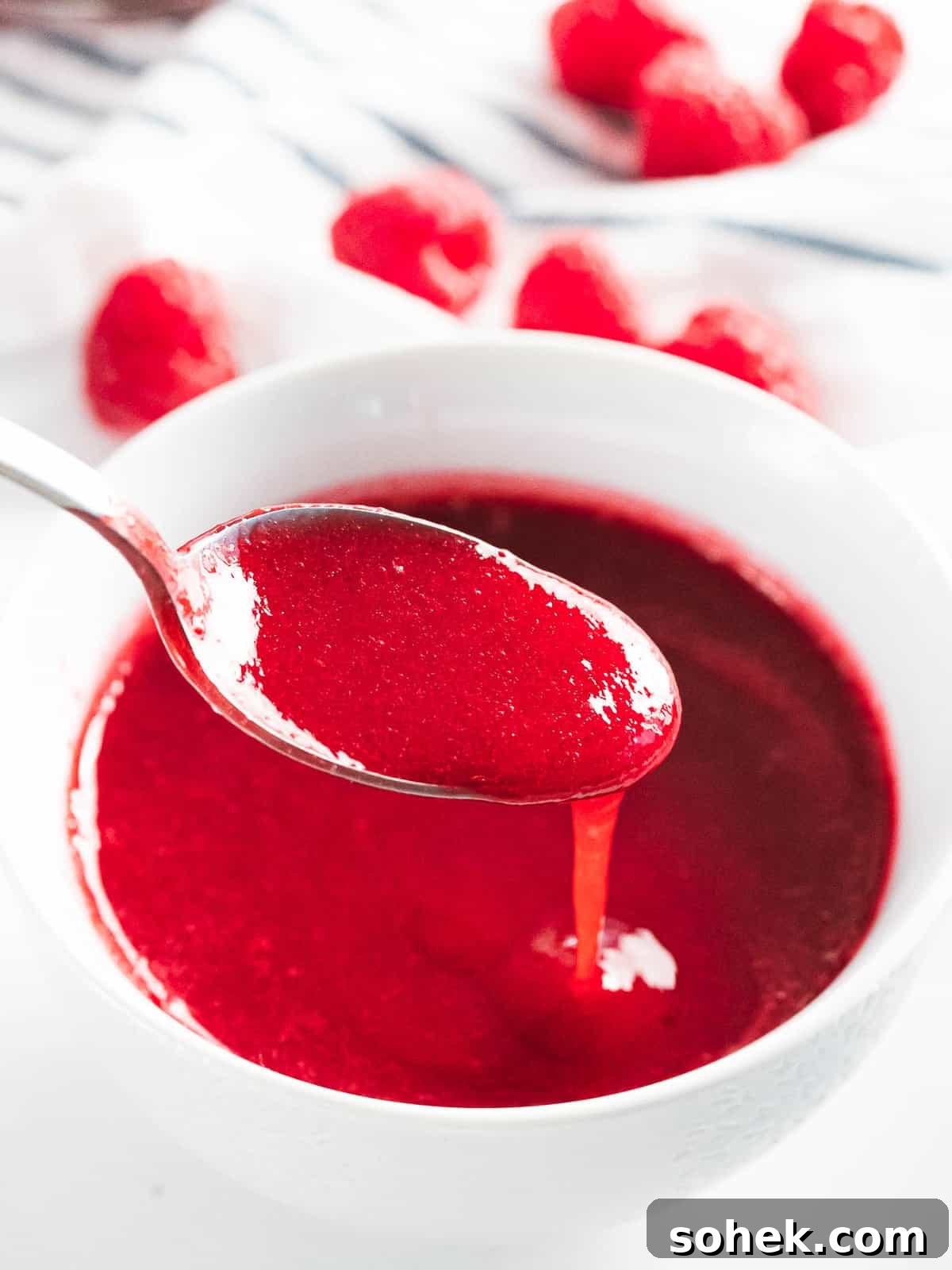 Homemade Raspberry Sauce Recipe for Desserts and Toppings 2 Raspberry sauce drizzled off a spoon.