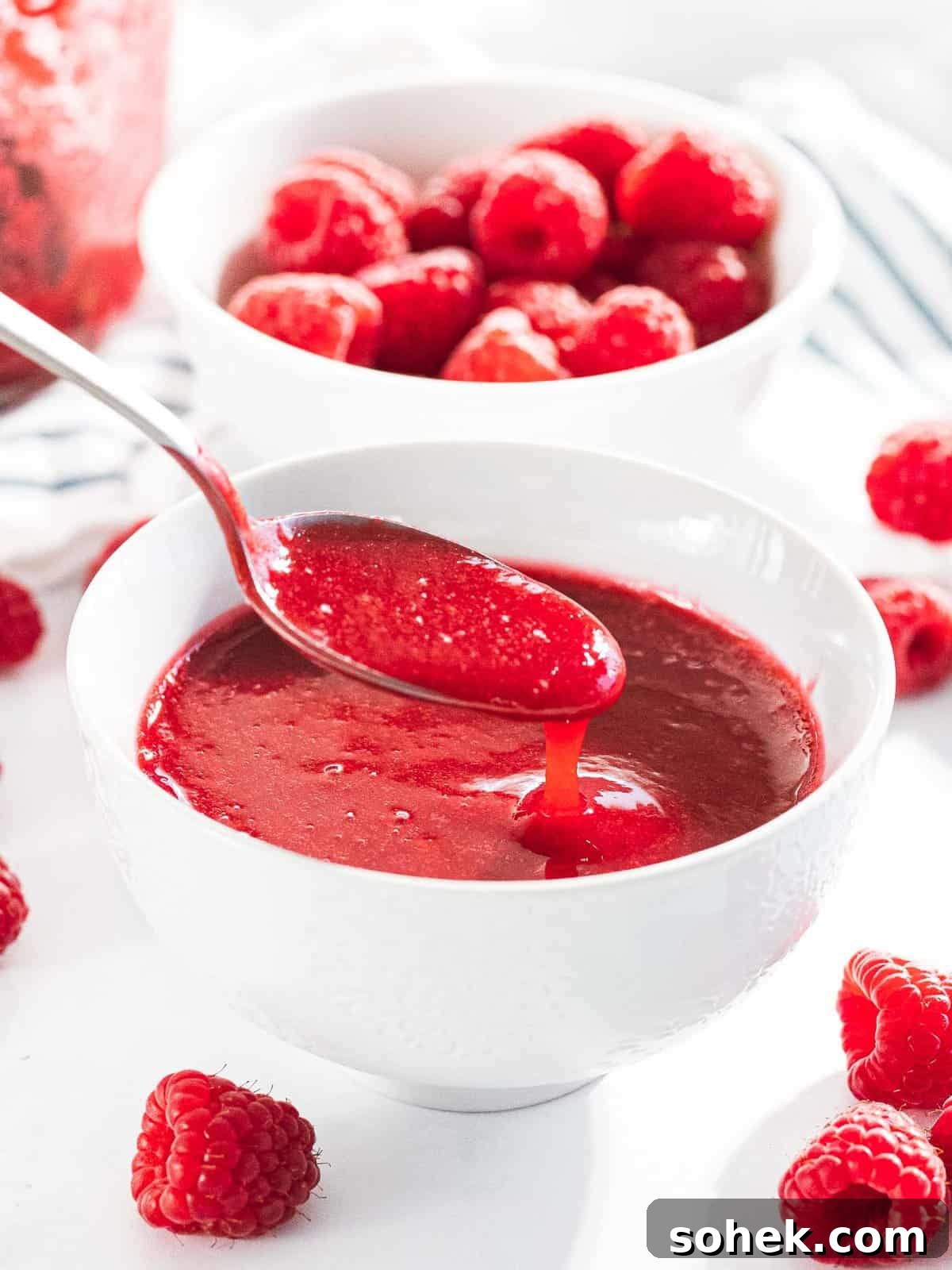 Homemade Raspberry Sauce Recipe for Desserts and Toppings 4 Raspberry sauce or raspberry coulis drizzled off a spoon into a bowl.