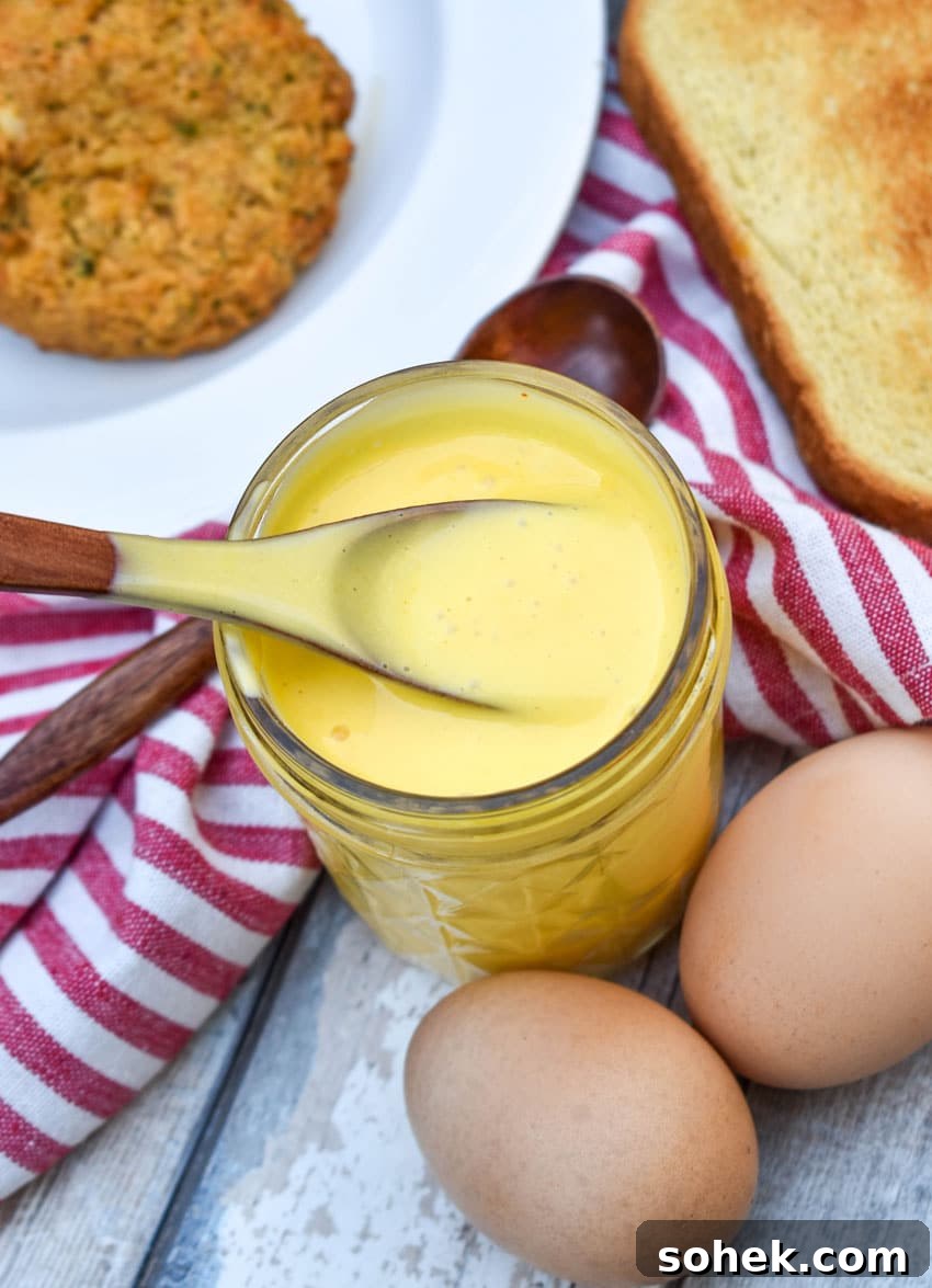 Quick Blender Hollandaise Sauce Recipe for Perfect Creamy Results 4 a wooden spoon scooping homemade hollandaise sauce out of a small glass jar