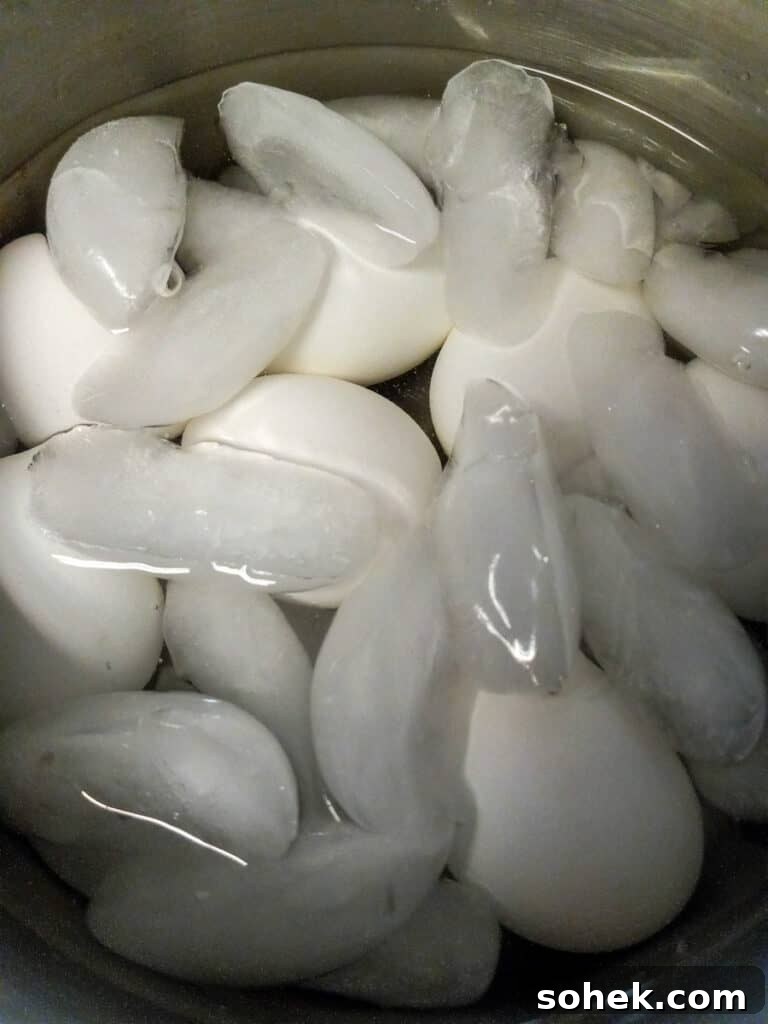 Authentic Amish Pickled Eggs and Beets Recipe for Tangy Flavor 4 boiled eggs covered in ice water.