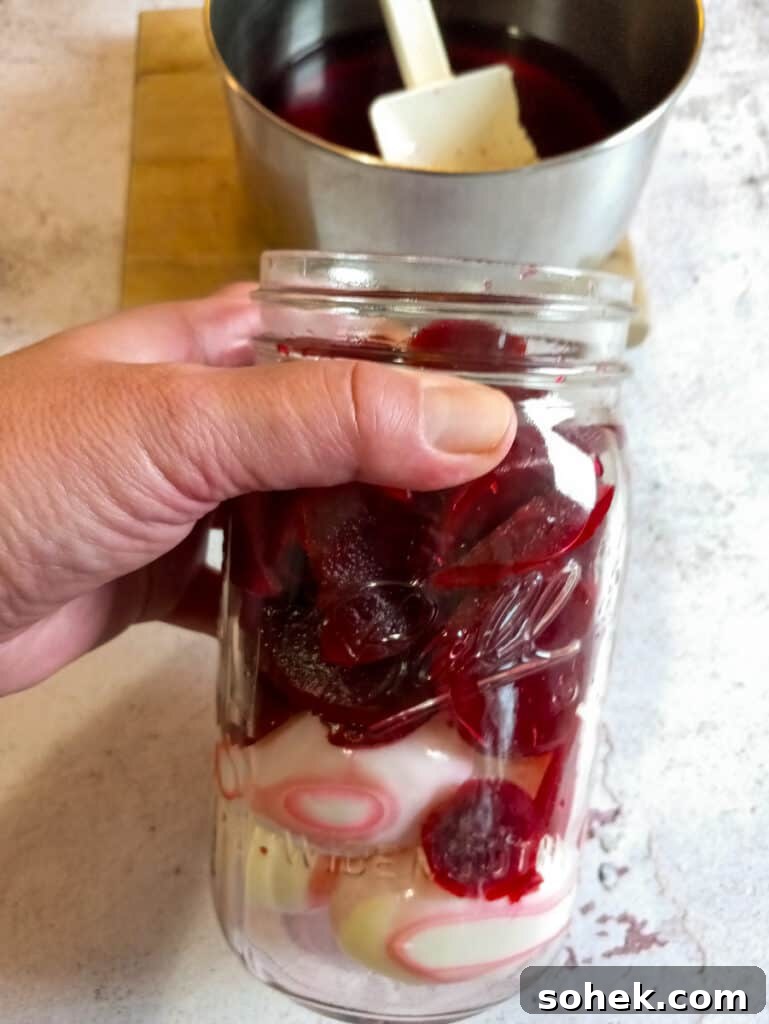 Authentic Amish Pickled Eggs and Beets Recipe for Tangy Flavor 8 eggs in a jar with beets on top, brine in a pot.