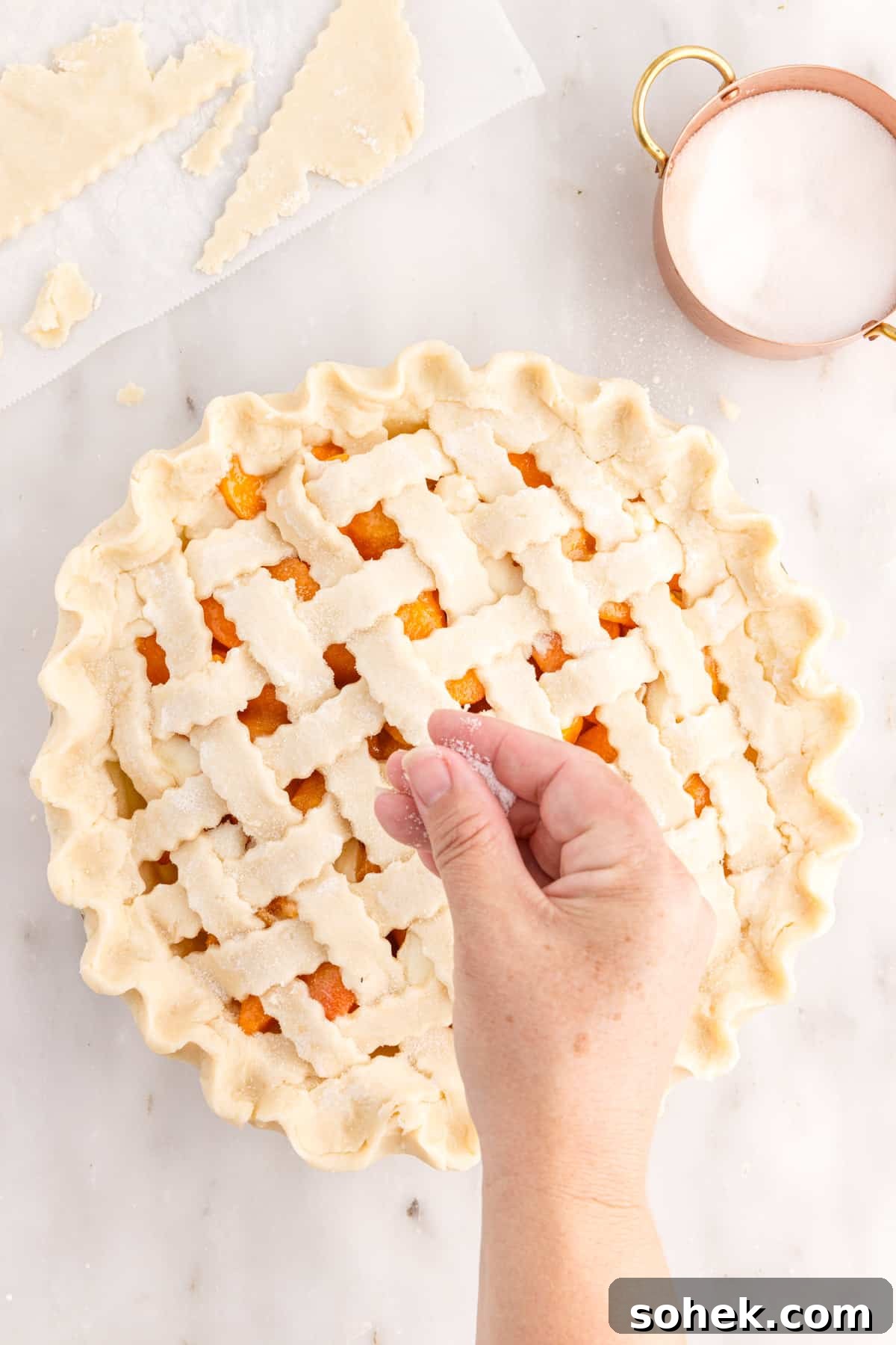 Sprinkling sugar over lattice top of apricot pie.