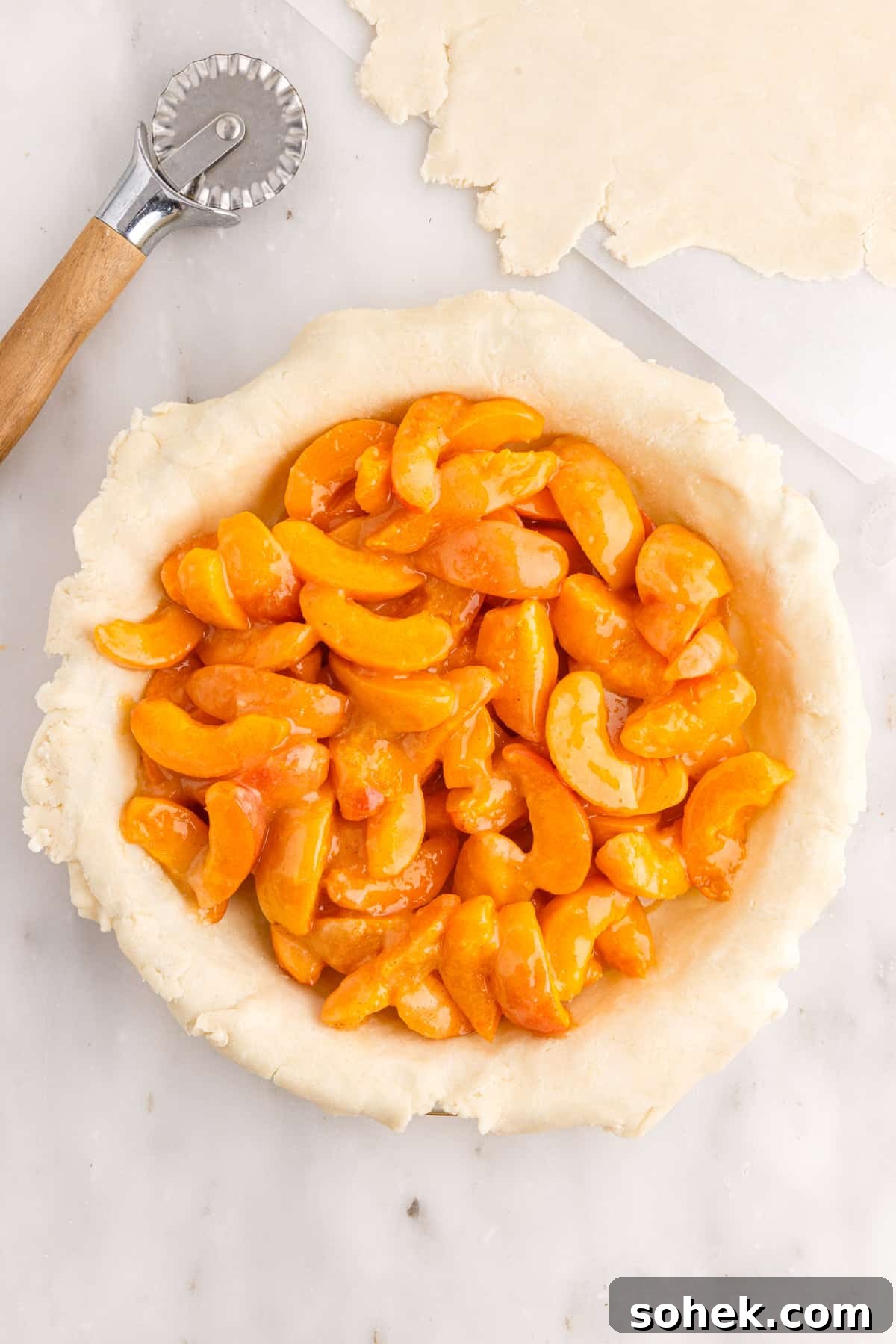Apricot pie filling mounded in unbaked pie crust in pie plate, strips of pie crust.