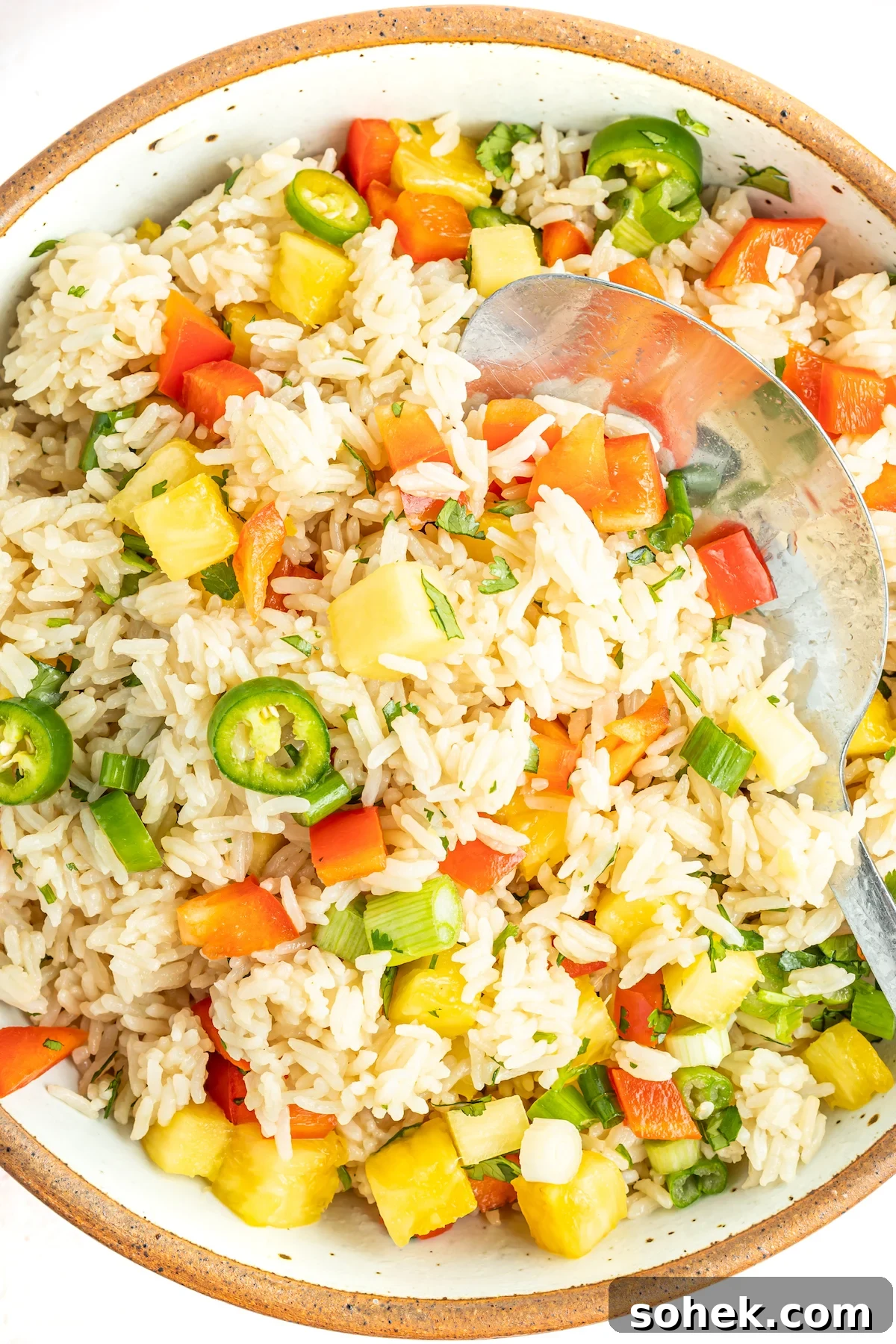A bowl filled with coconut rice made in the Instant Pot with chopped pineapples, jalapeno slices, and red bell pepper.