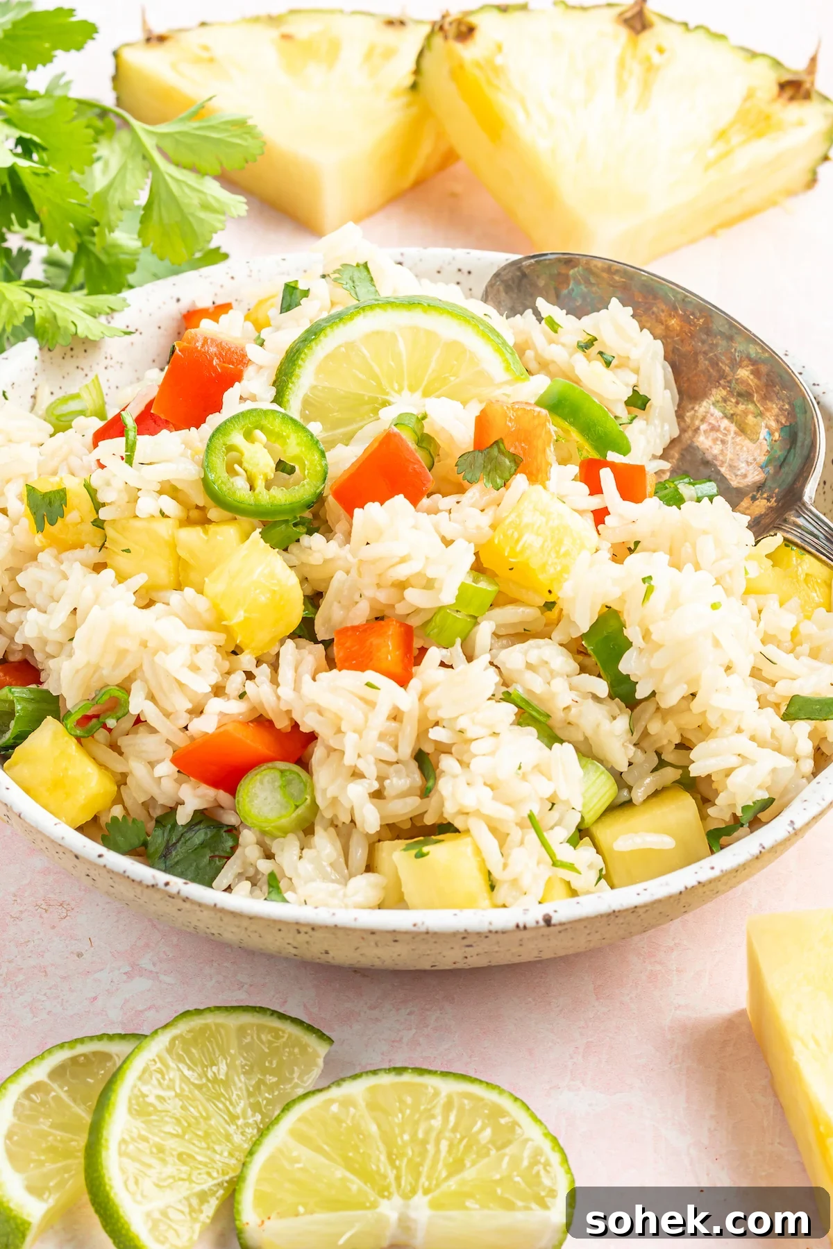 A serving bowl filled with instant pot coconut rice that has chopped pineapple, green onions, jalapenos, and red bell pepper.