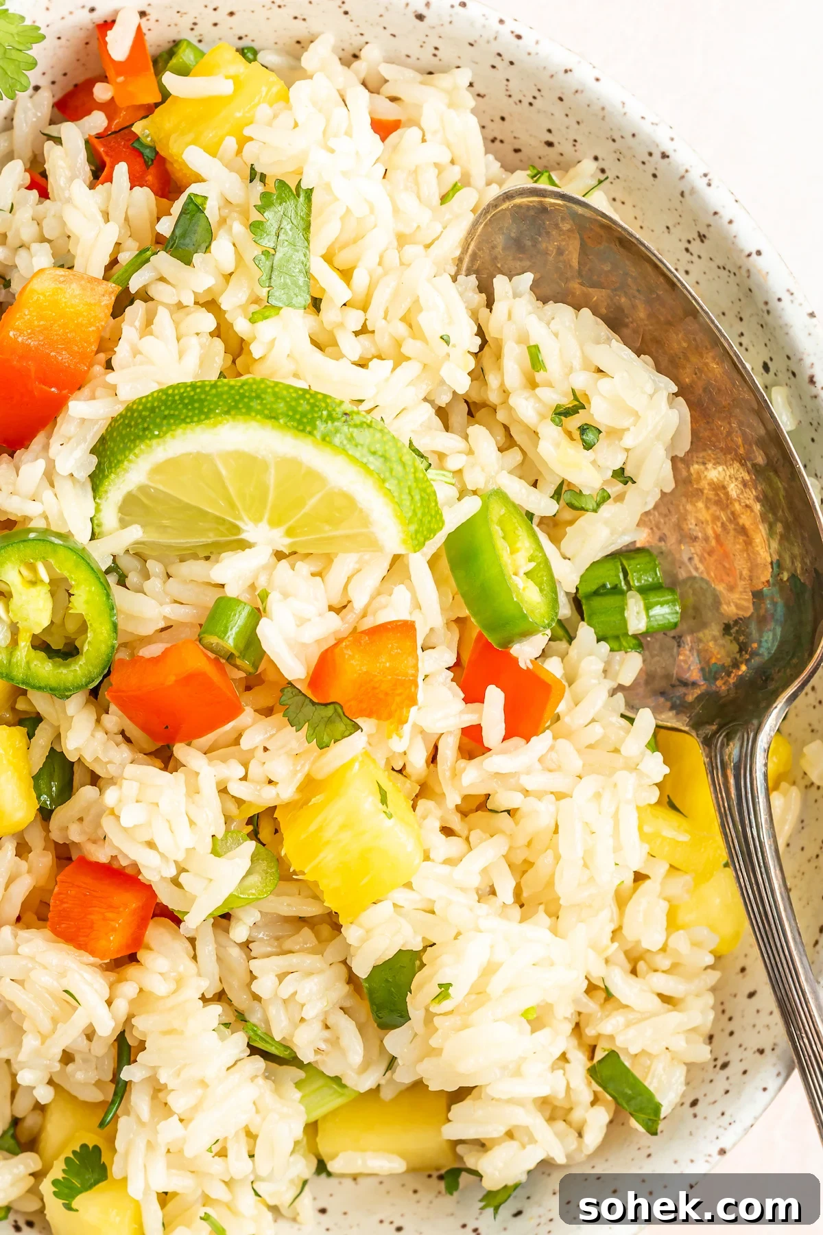 A serving bowl filled with white Instant Pot coconut rice with pineapple and peppers.