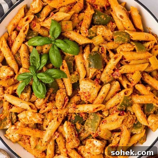 A bowl of one pan Cajun Chicken Pasta, ready to serve, with basil on top.