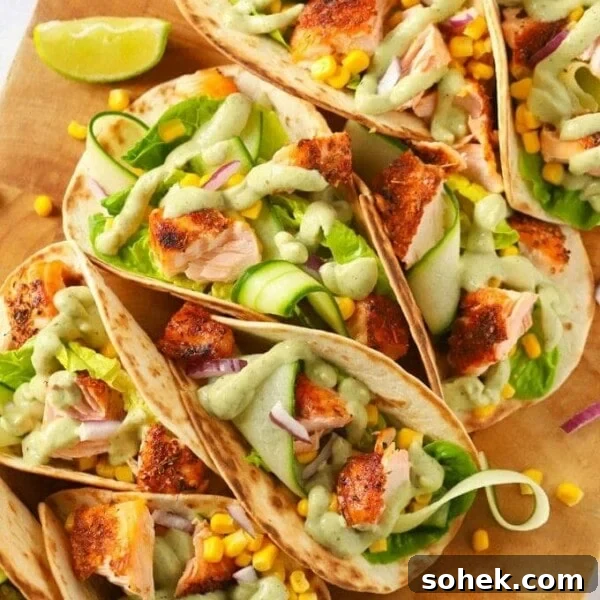 Easy salmon tacos recipe on a wooden board with cucumber and avocado dressing