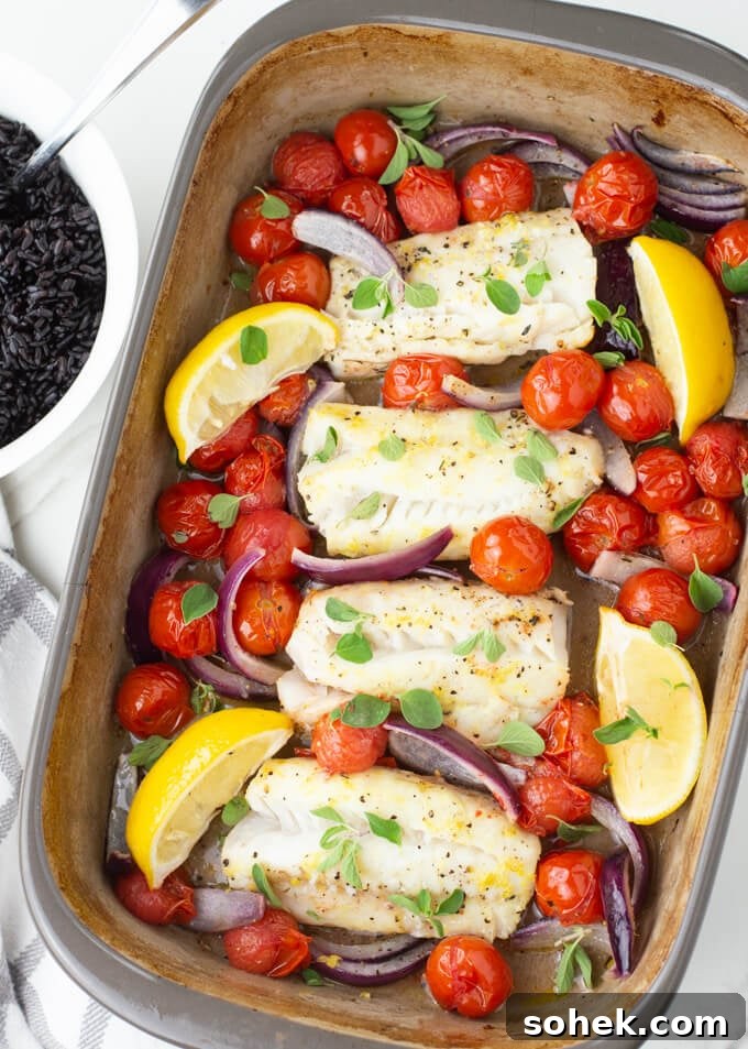 Oven-Baked Cod with Roasted Blistered Tomatoes 6 Baked Cod with cherry tomatoes, red onions and lemon wedges are in a baking dish with fresh oregano scattered on top. A bowl of black rice sits next to it.