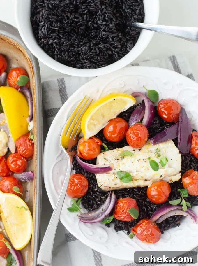 Oven-Baked Cod with Roasted Blistered Tomatoes 8 A white dish with baked cod and cherry tomatoes over black rice with a lemon wedge. The baking pan of cod and a bowl of black rice sit next to the dish.