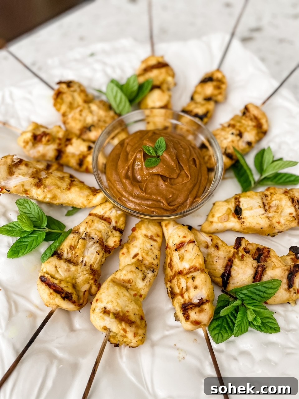 Asian Chicken Skewers with Creamy Peanut Dipping Sauce 2 The finished Asian Chicken Skewers with Peanut Dipping Sauce on a plate with green garnish