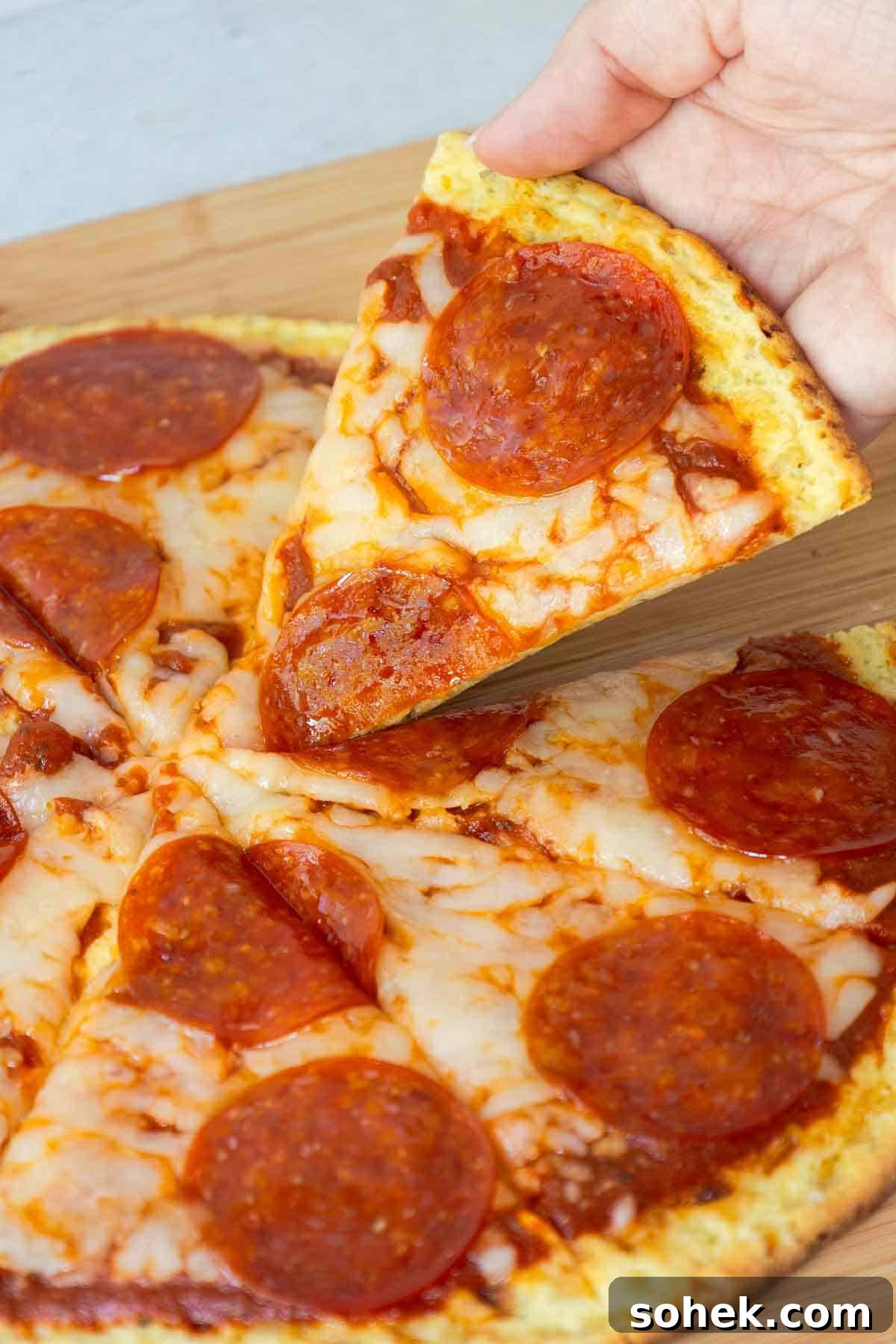 Cottage Cheese Pizza Crust Recipe: Thin, Chewy Low-Carb Base 12 A hand lifting a slice of pepperoni pizza from the rest of the pie.