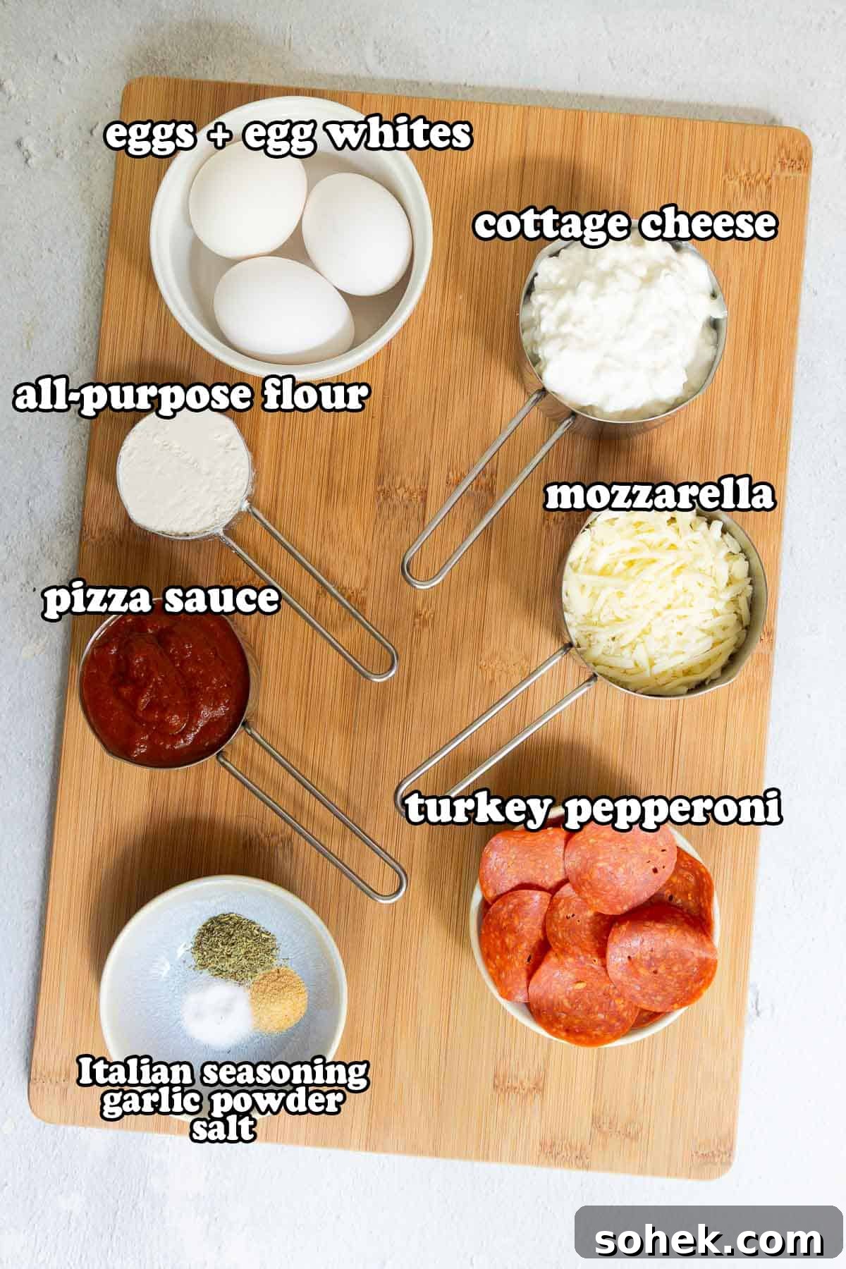 Cottage Cheese Pizza Crust Recipe: Thin, Chewy Low-Carb Base 3 Ingredients arranged on a cutting board. Text on the image says 'eggs + egg whites', 'all-purpose flour', 'pizza sauce', 'Italian seasoning garlic powder salt', 'cottage cheese', 'mozzarella', 'turkey pepperoni'.