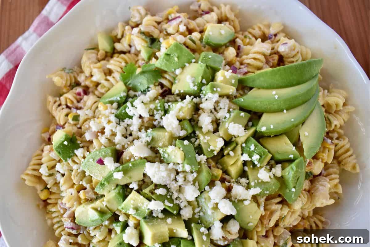 Mexican Elote Pasta Salad: Creamy Street Corn Pasta Recipe 3 Overhead photo of elote pasta salad with avocado and cotija cheese on top.