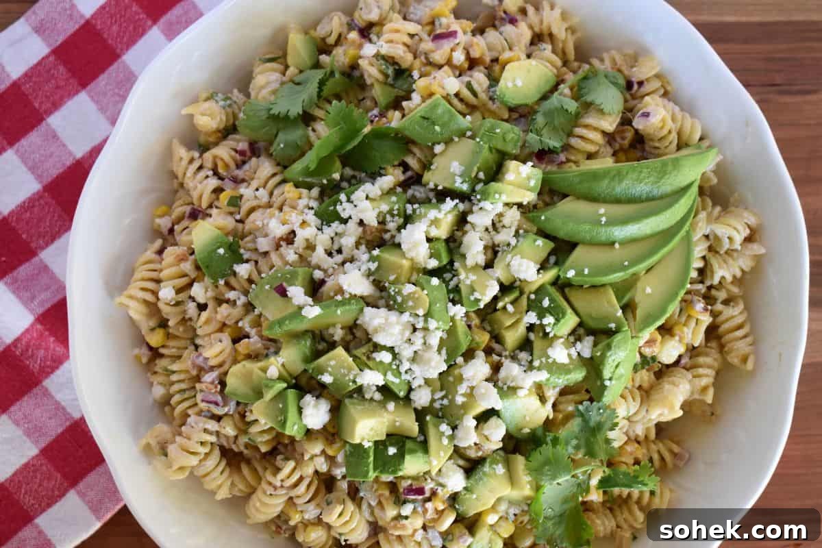 Mexican Elote Pasta Salad: Creamy Street Corn Pasta Recipe 5 Elote Pasta Salad in a white bowl with a checkered napkin underneath.