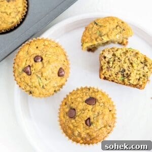 Banana Zucchini Chocolate Chip Muffins Recipe 9 Two whole and two half banana zucchini chocolate chip muffins on a white plate.