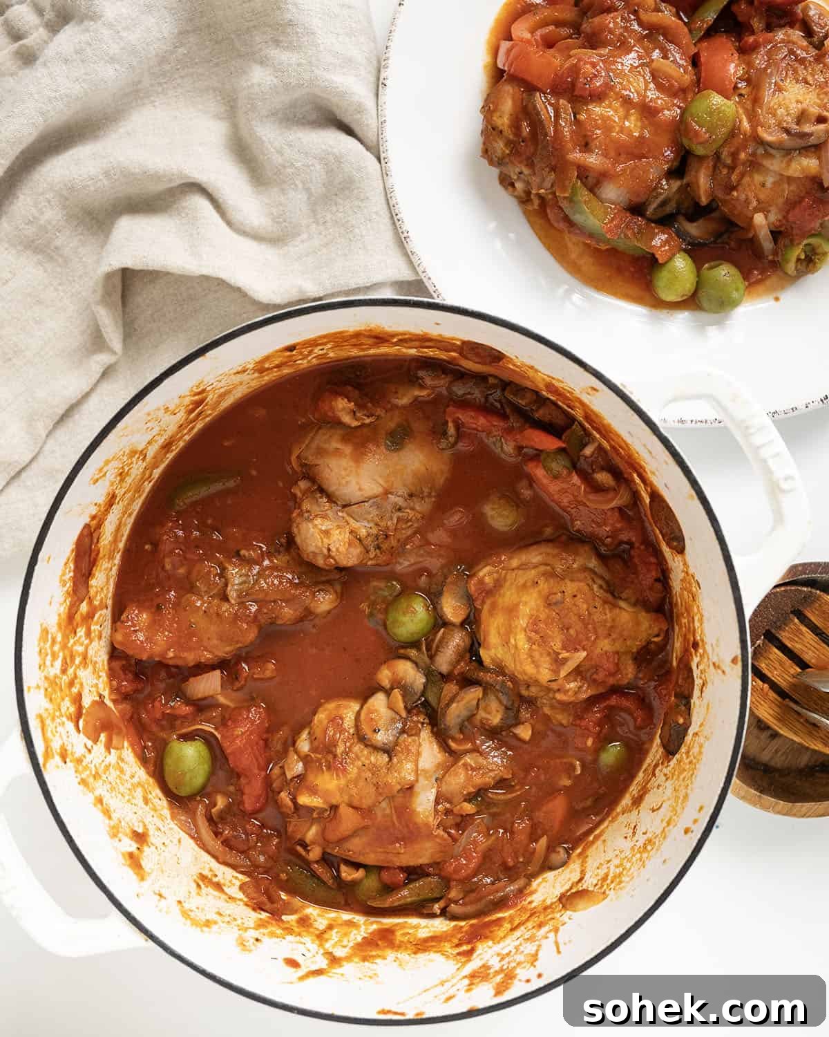 Finished chicken cacciatore on a plate and the remaining in a dutch oven. 