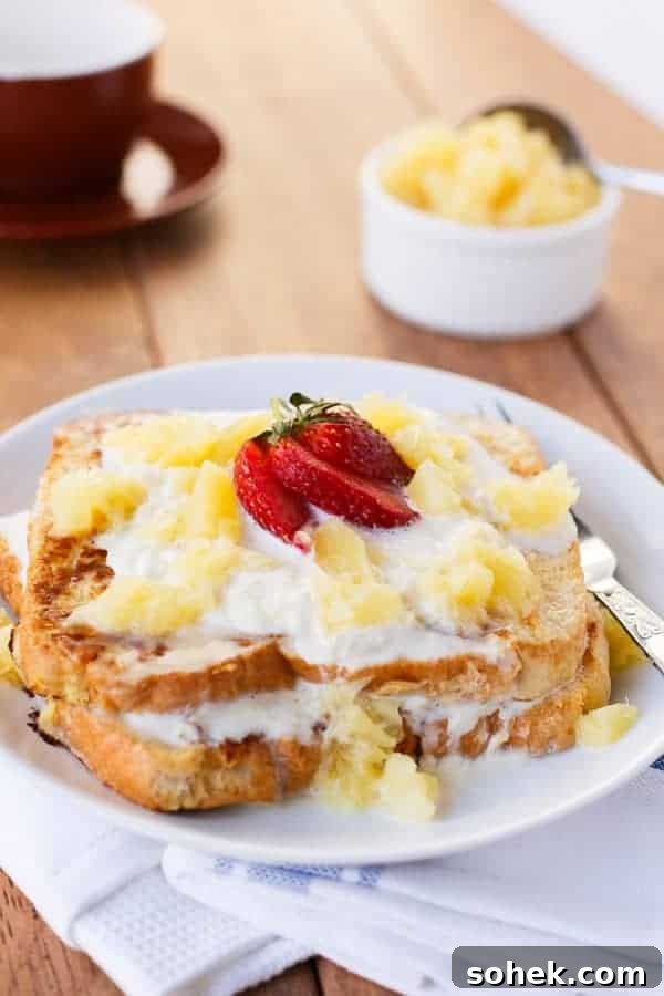 Pineapple Coconut French Toast Recipe — Piña Colada Flavor 8 Pina Colada French Toast on a plate with some fresh strawberry pieces