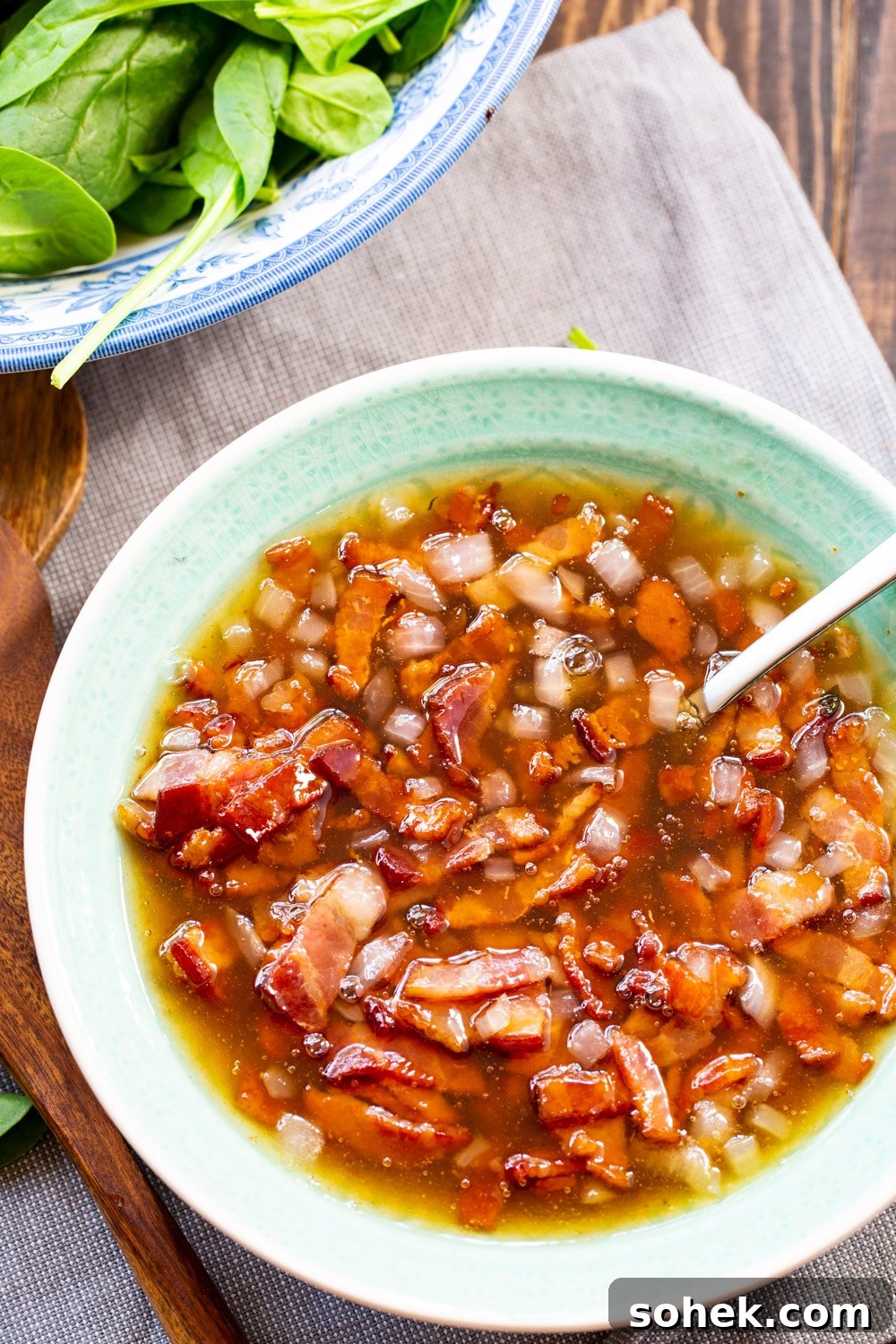 Hot Bacon Dressing in bowl with a spoon.