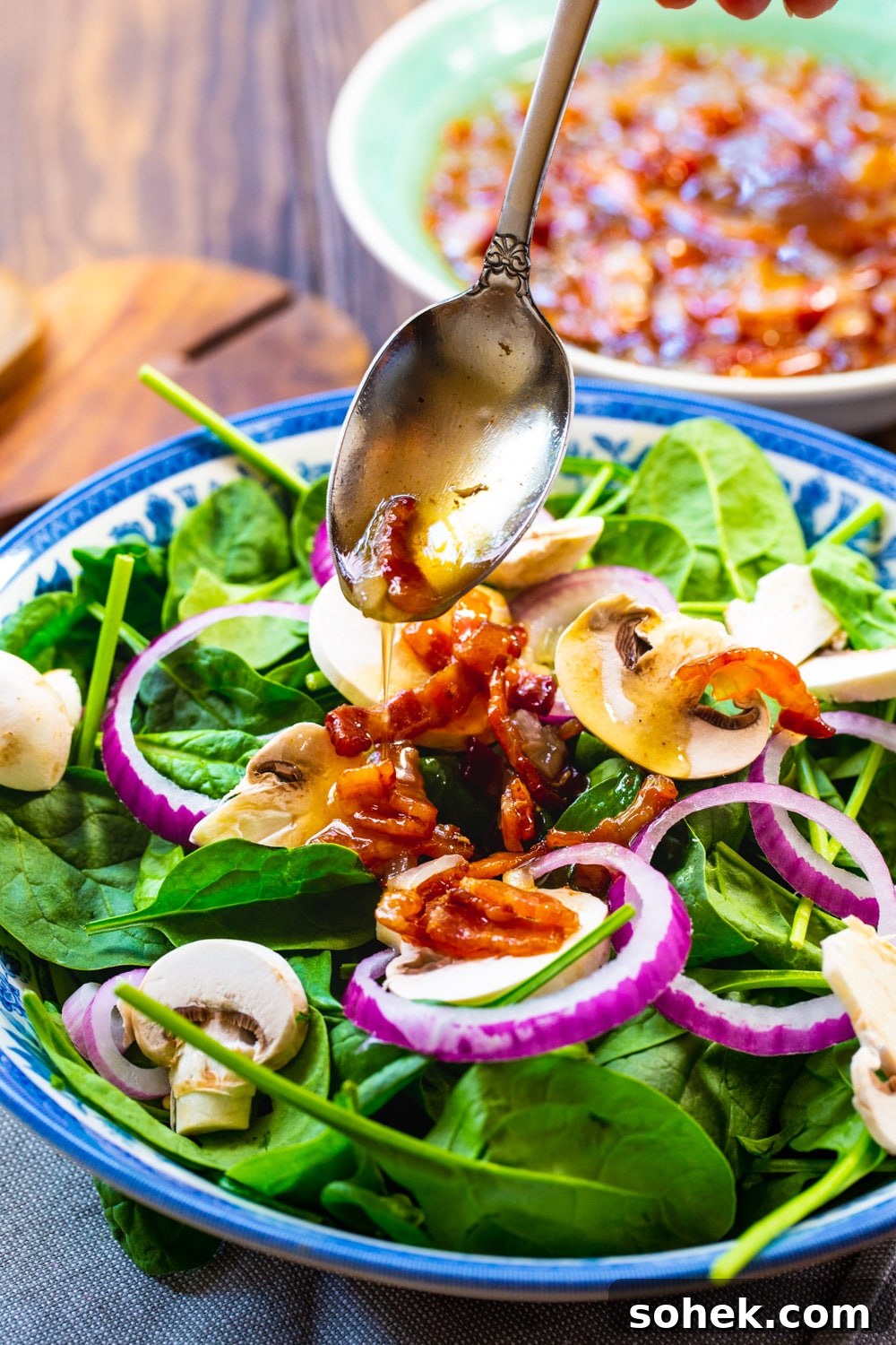 Dressing being spooned over salad.