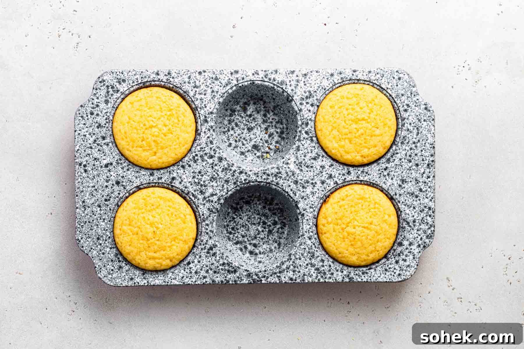 Zesty Lemon Cupcakes Recipe with Luscious Lemon Frosting 10 Four lemon cupcakes in a muffin pan, after baking.