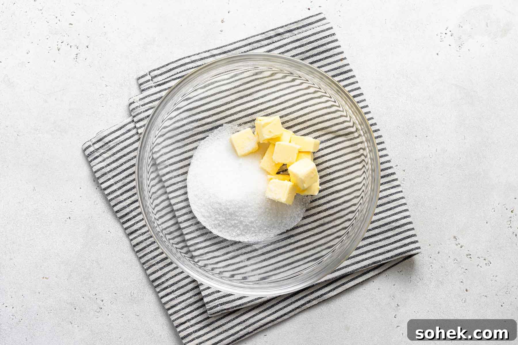 Zesty Lemon Cupcakes Recipe with Luscious Lemon Frosting 15 Diced butter and granulated sugar in clear glass bowl.