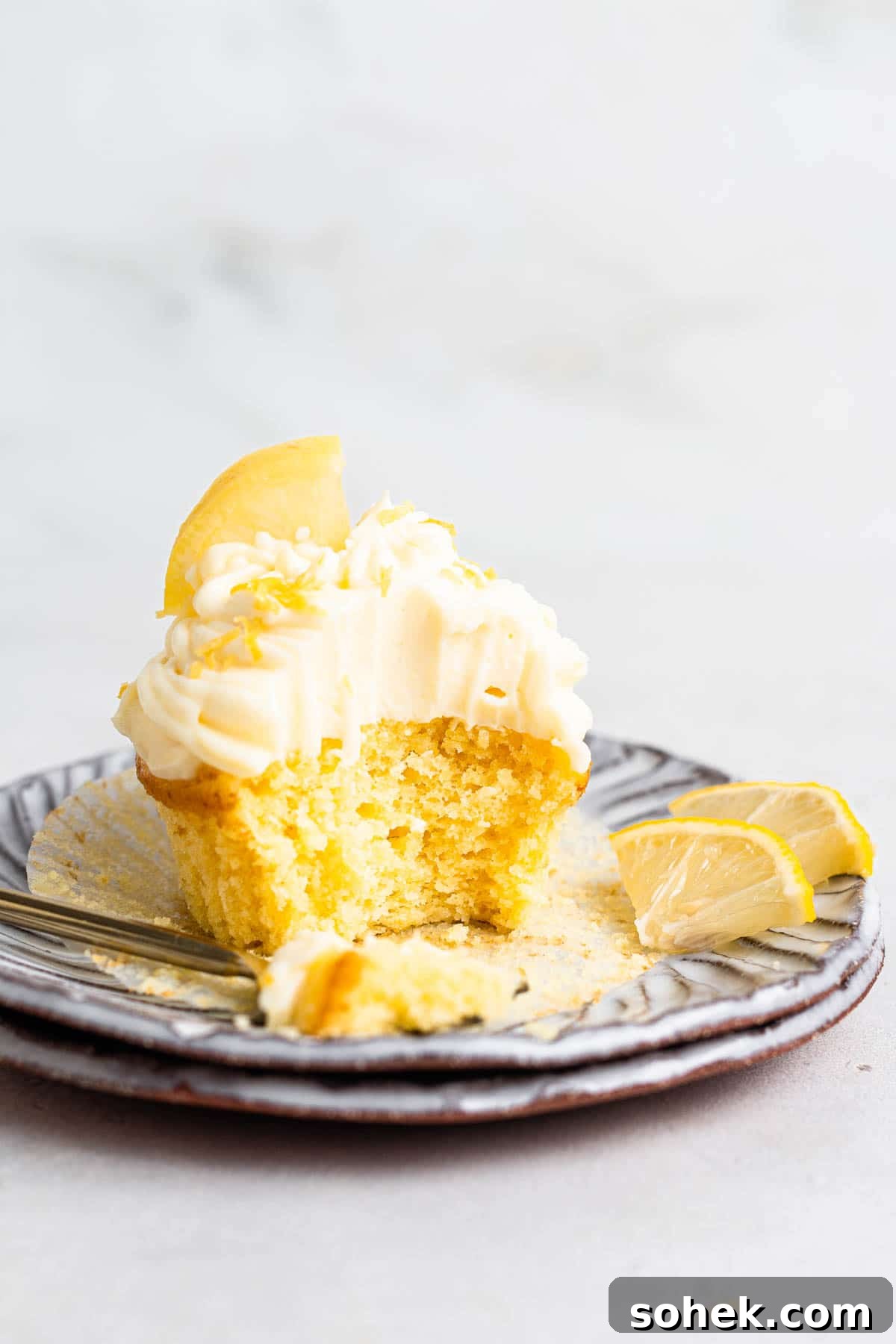 Zesty Lemon Cupcakes Recipe with Luscious Lemon Frosting 3 Single lemon cupcake with lemon cream cheese frosting on a plate.