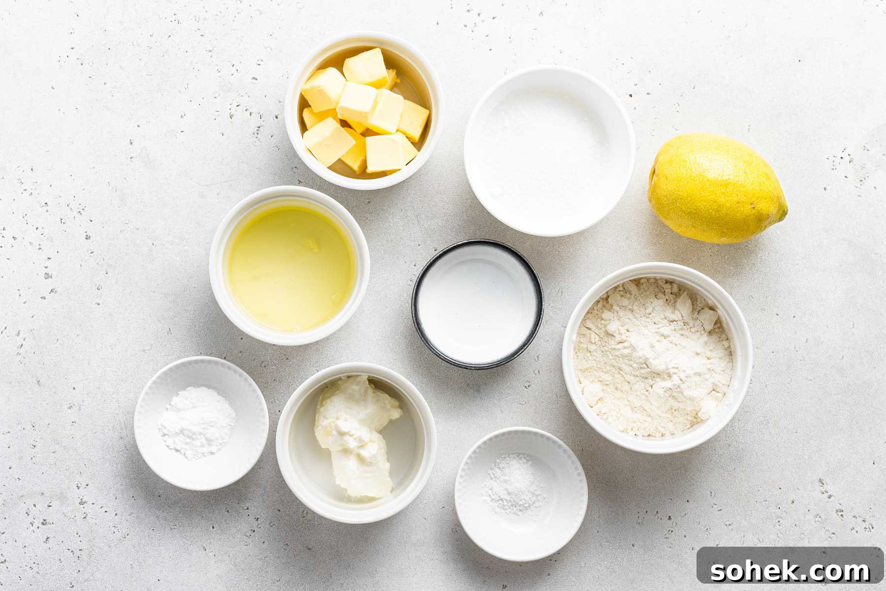 Zesty Lemon Cupcakes Recipe with Luscious Lemon Frosting 4 Ingredients for lemon cupcakes measured in white bowls.